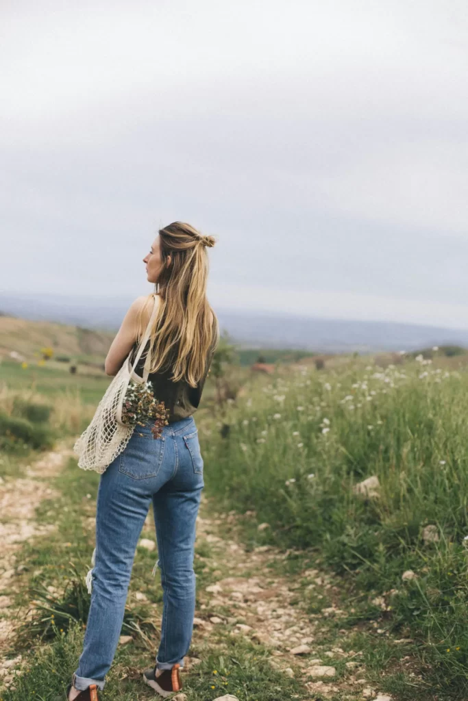 Rozjímající žena stojící na poli a hledící do dálky, což evokuje momenty sebereflexe a spojení s přírodou